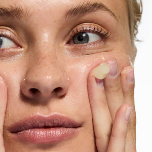 Model squeezing Oat Cleansing Balm onto her hand