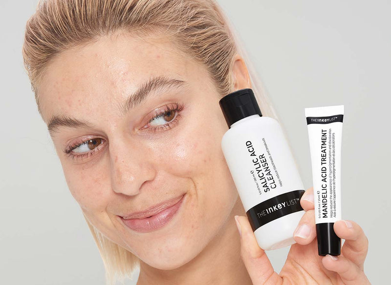 Model holding Salicylic Acid Bottle and Mandelic Acid Treatment next to her face