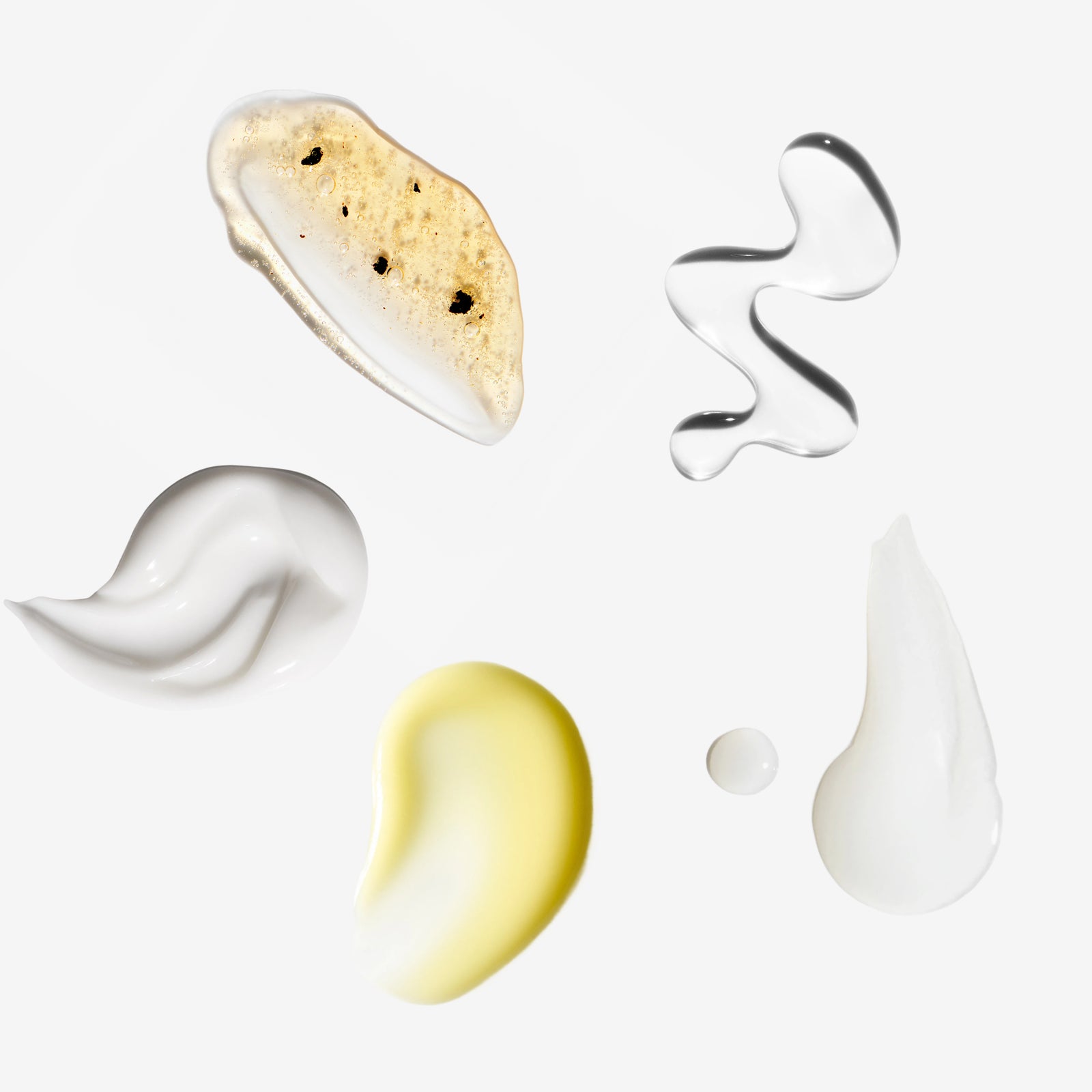 Various shaped and colored cream samples on a white background