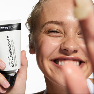 Person holding a skincare product with a close-up of their face.