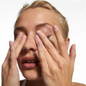 Close-up of a person with hands covering their face on a white background