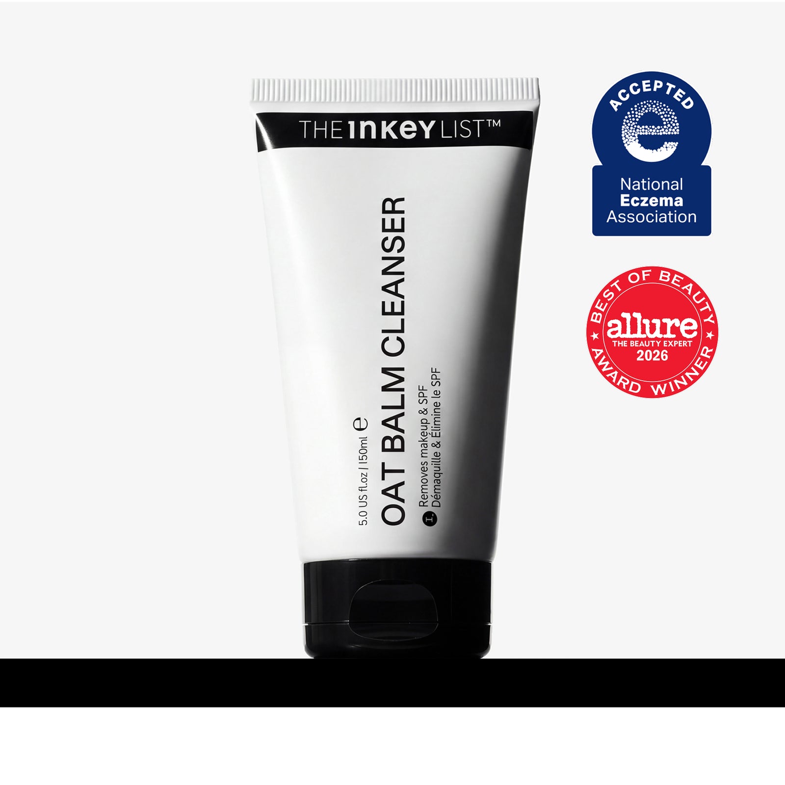 A white tube of The Inkey List Oat Balm Cleanser with a black cap, shown on a light gray background with two award badges on the right: a blue National Eczema Association Accepted badge and a red Allure Best of Beauty 2024 award badge.
