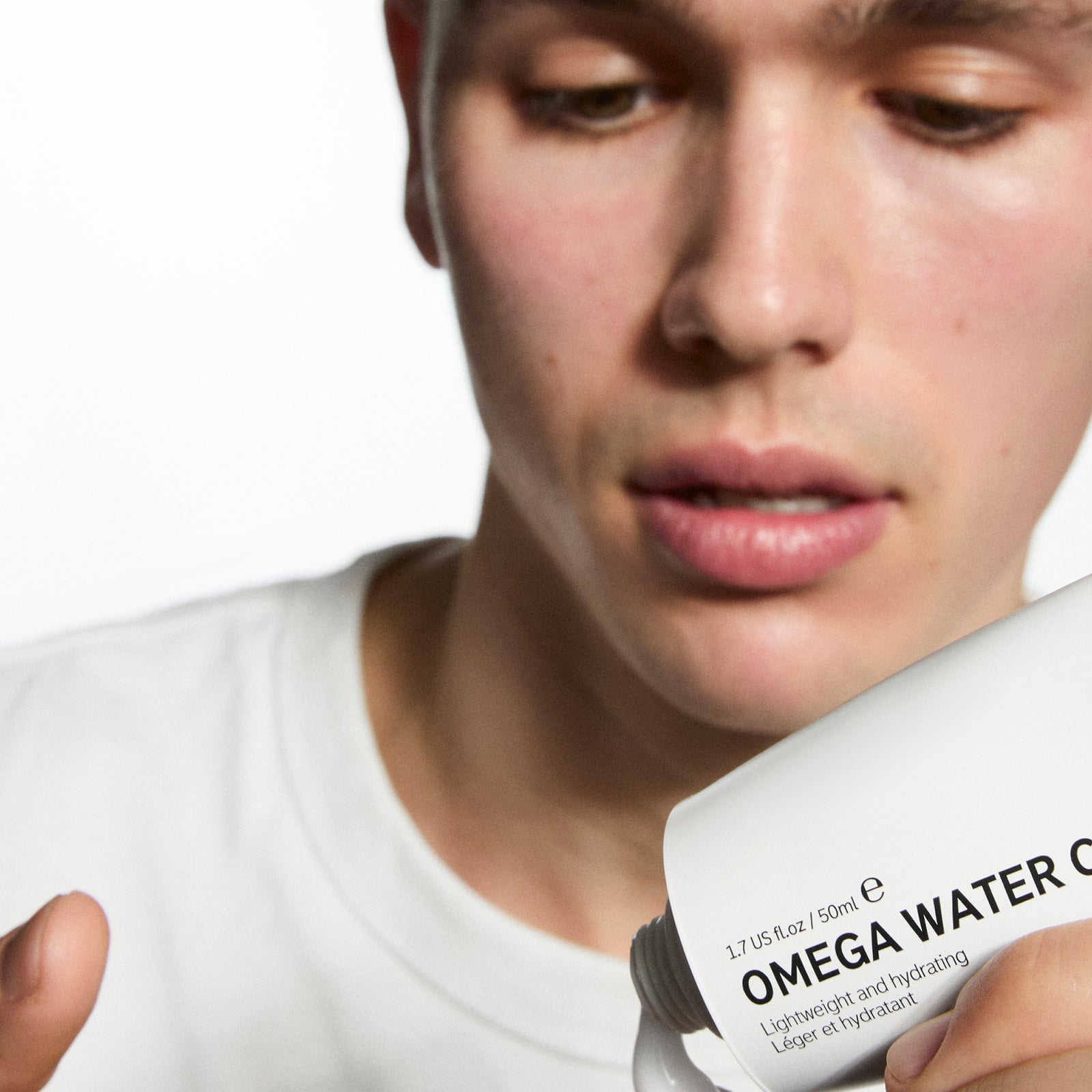 Person holding a bottle labeled 'Omega Water' with a blurred background