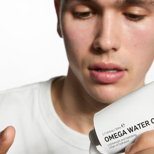 Person holding a bottle labeled 'Omega Water' with a blurred background