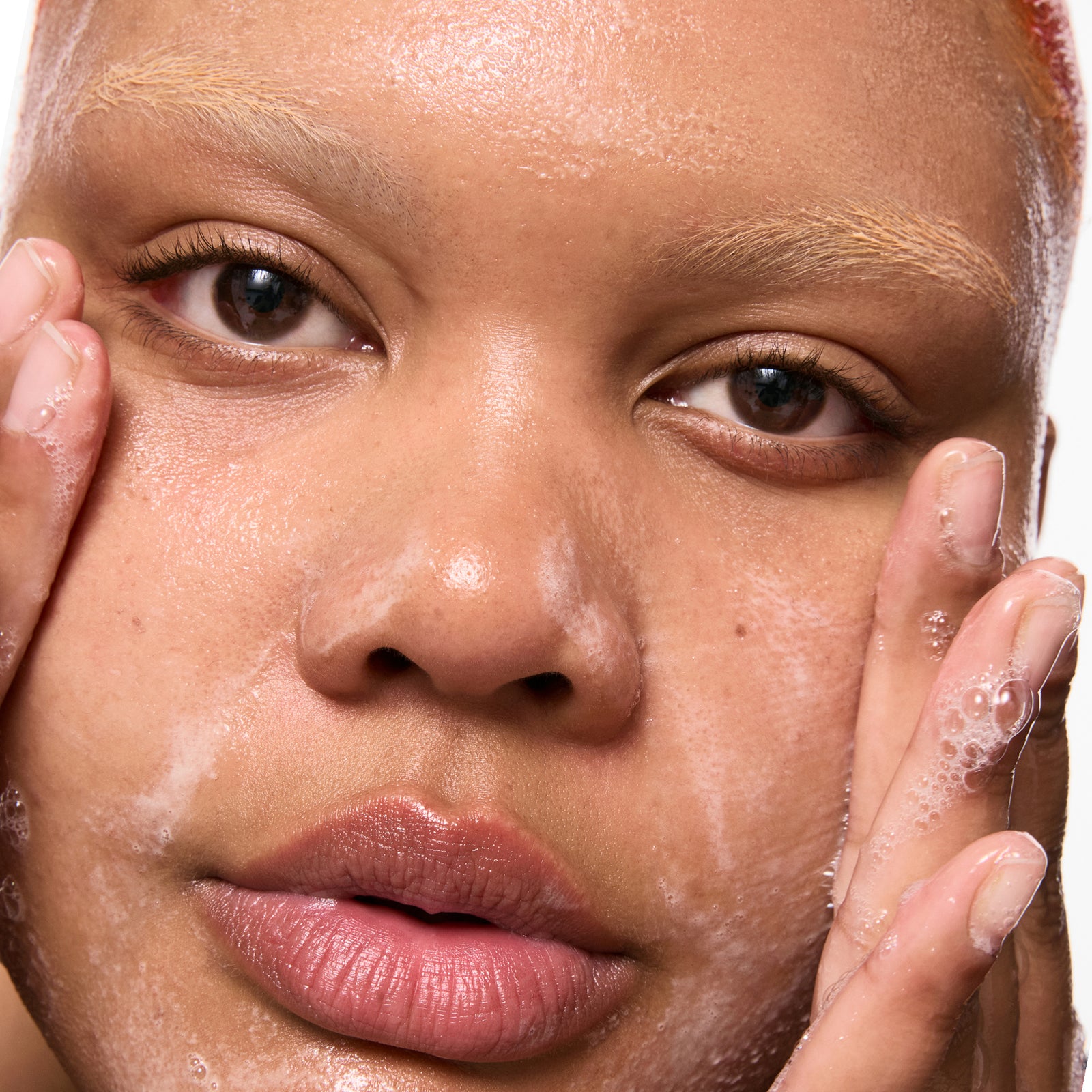 Close-up of a person applying a Salicylic Acid Cleanser to their face.
