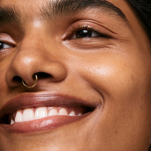 Close-up of a person's face with a smile, wearing a nose ring.