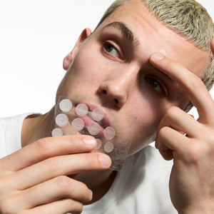 Person holding Hydrocolloid Invisible Patches against a white background.