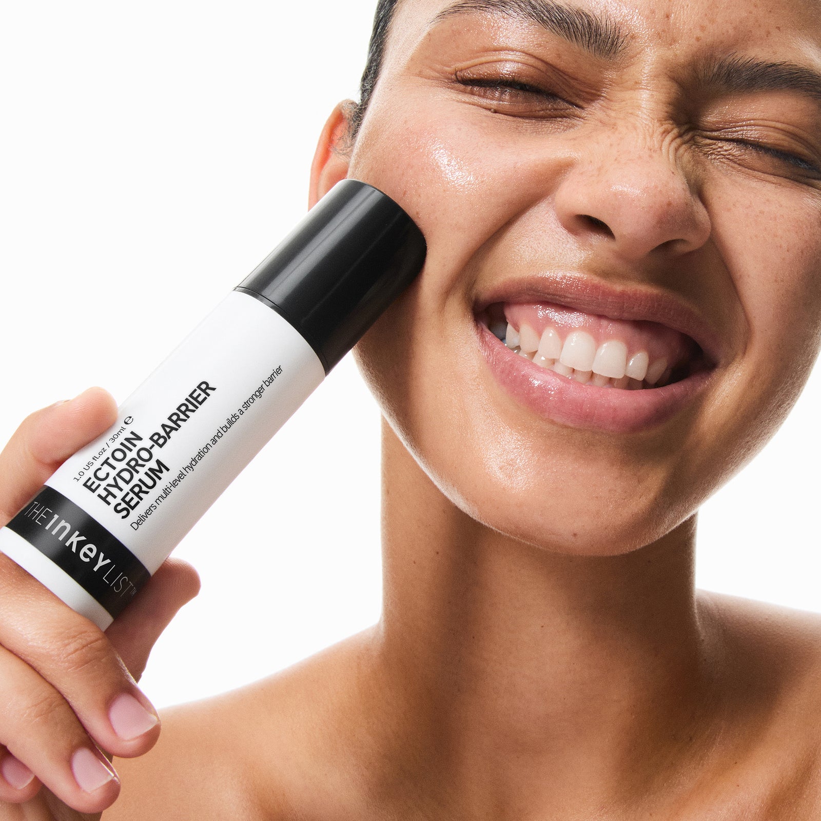 Woman applying Ectoin Hydro-Barrier Serum to her face with a white background