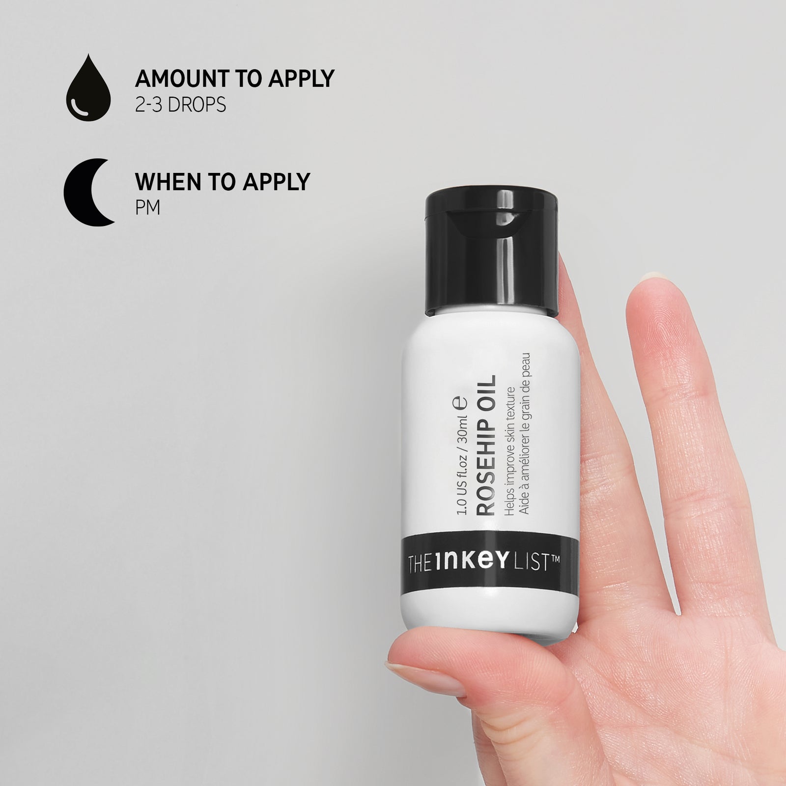 Hand holding Rosehip Oil bottle on grey background with black text explaining how and when to use it with texts that reads 'Amount to apply (2-3 drops)' and 'When to apply (PM)'